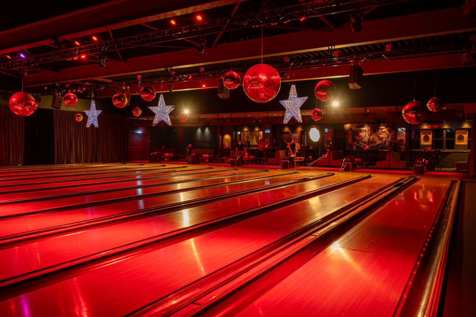 De bowlingbanen in rood licht, met rode kerstballen en lichtsterren aan het plafond