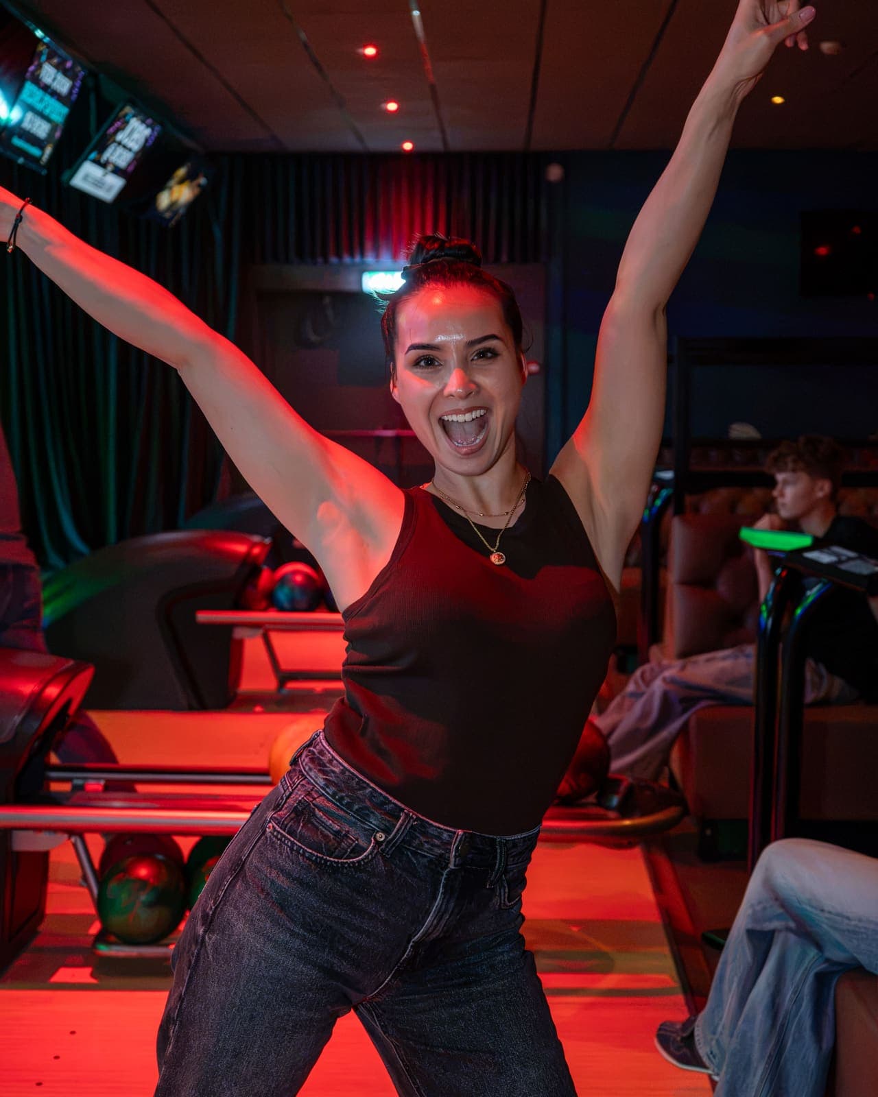 Een gast juicht met beide armen omhoog op de bowlingbaan