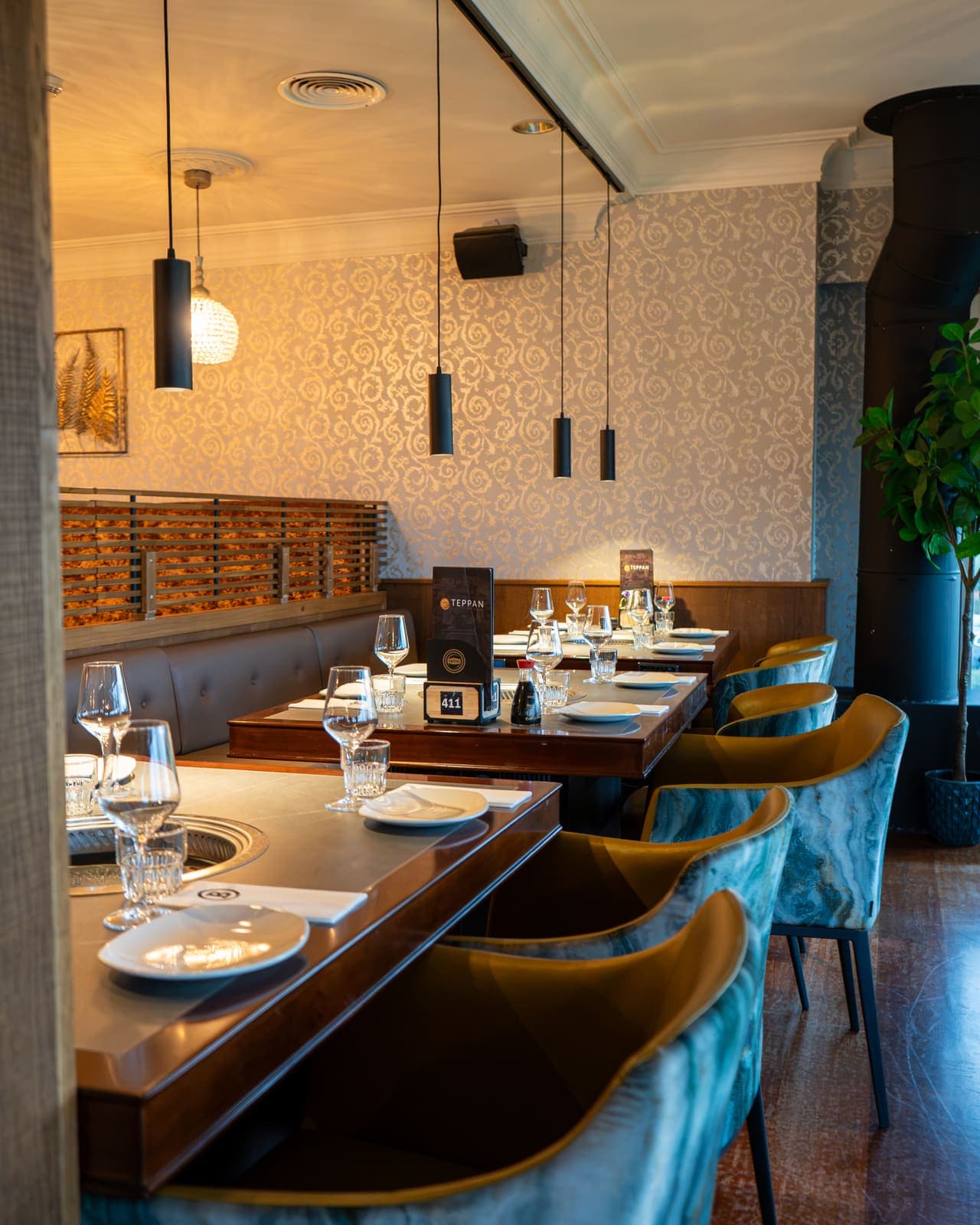 Een rij grilltafels met groene stoelen onder hanglampen