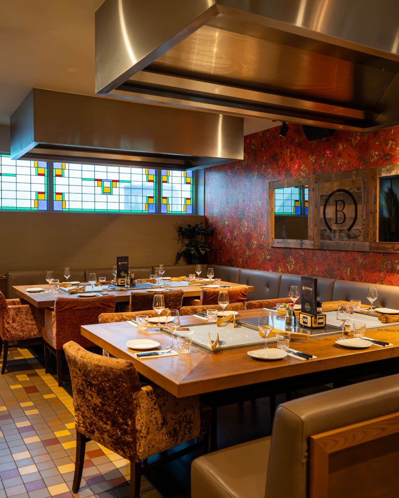 Een hoek van het restaurant met glas-in-lood en bloemenbehang