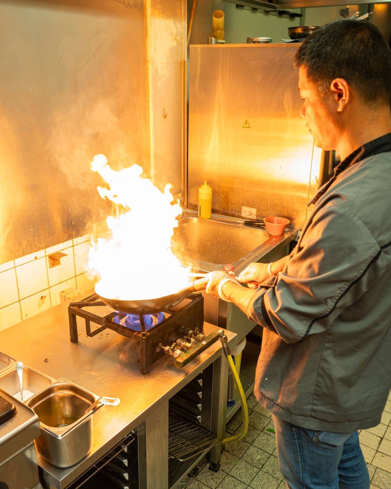 Een kok laat de vlammen uit de wok slaan in de keuken