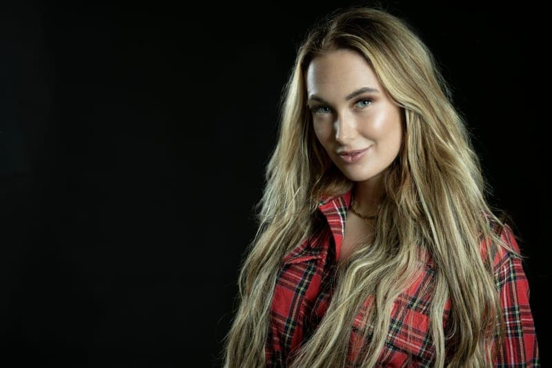Boerin Anna in een rood geruite blouse, lachend in de camera