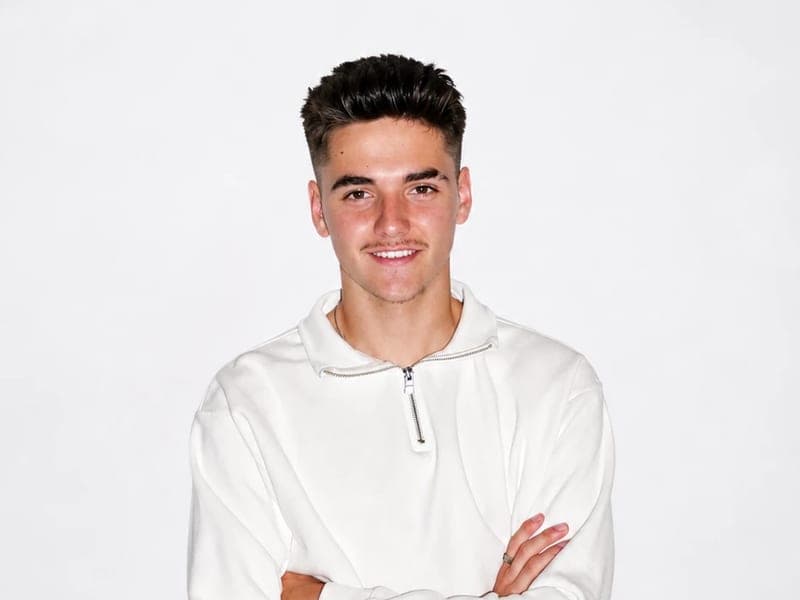 DJ Dlano in een witte trui met de armen over elkaar
