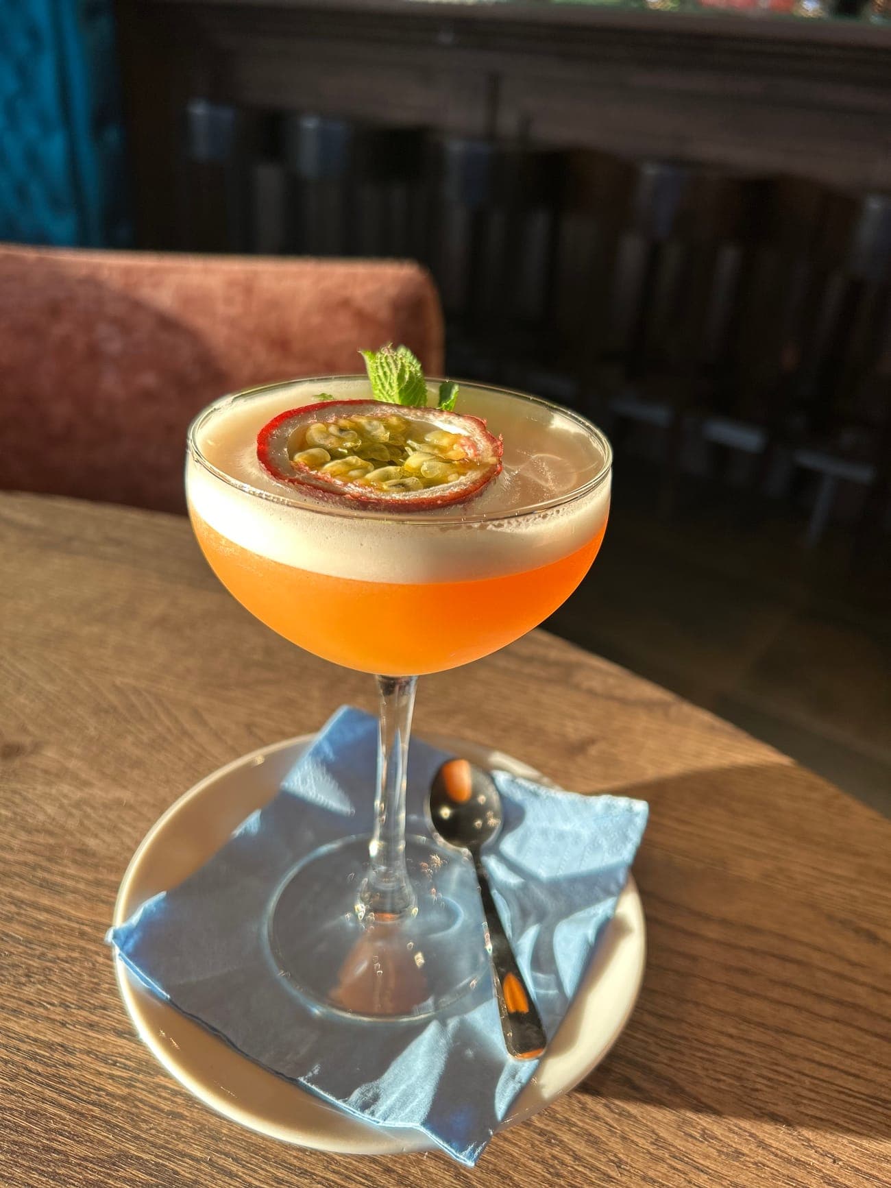 Een cocktail met een schijf passievrucht op de schuimlaag, op de bar