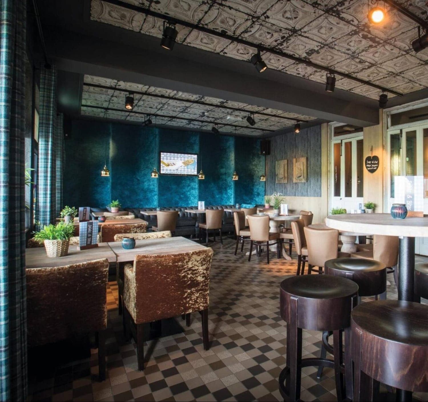 Het Grand Café met de bar achterin, hoge tafels en zitbanken ervoor