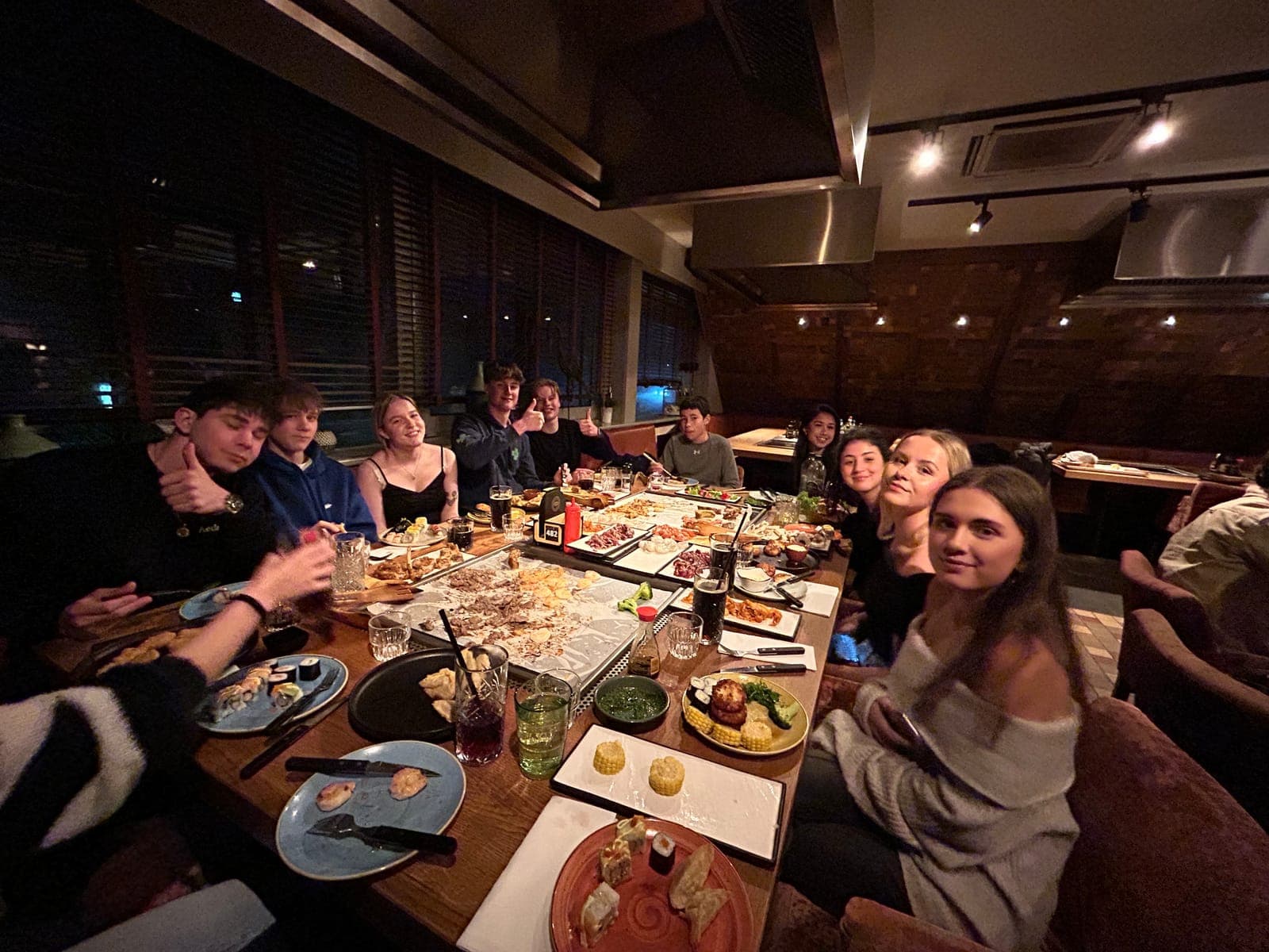 Een groep aan een lange tafel vol schalen, midden in het eten