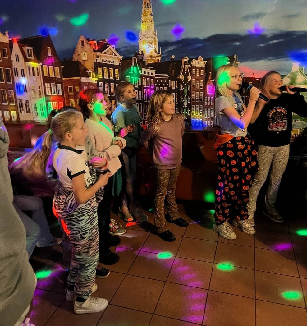 Gasten zingen samen met de microfoon in de karaokebar, onder gekleurde lichtvlekken
