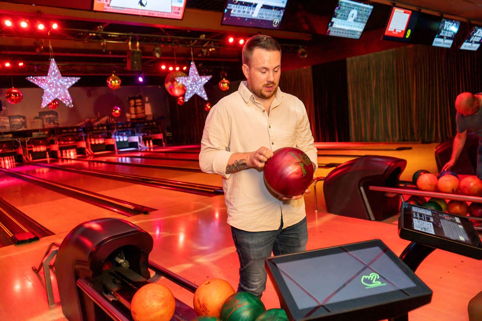Een gast met een rode bowlingbal naast het scorescherm