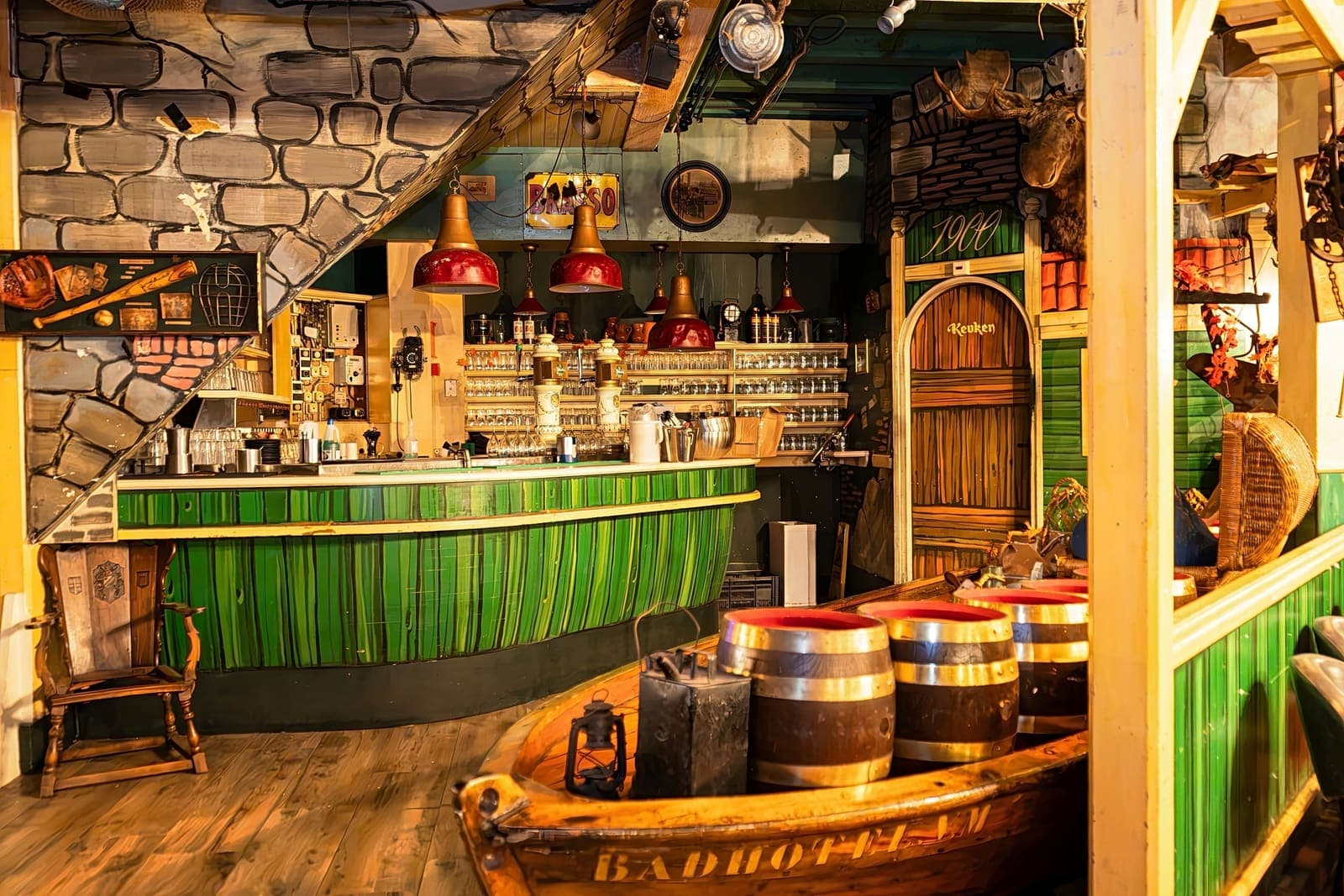 De groene bar van Brasserie 1900, met een houten sloep vol vaten ervoor