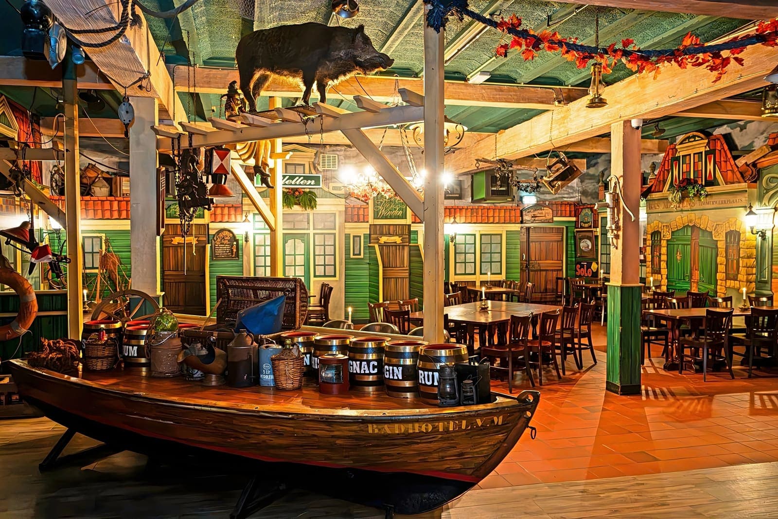 Een houten sloep met rum- en cognacvaten midden in de zaal, met de geveltjes erachter