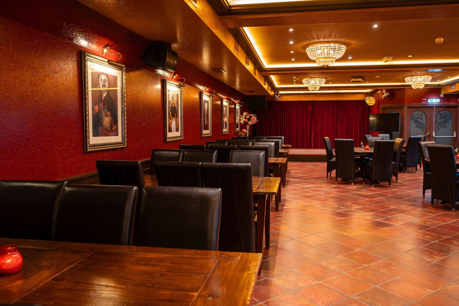 Een lange tafel langs de portrettenwand, de zaal en het podium erachter