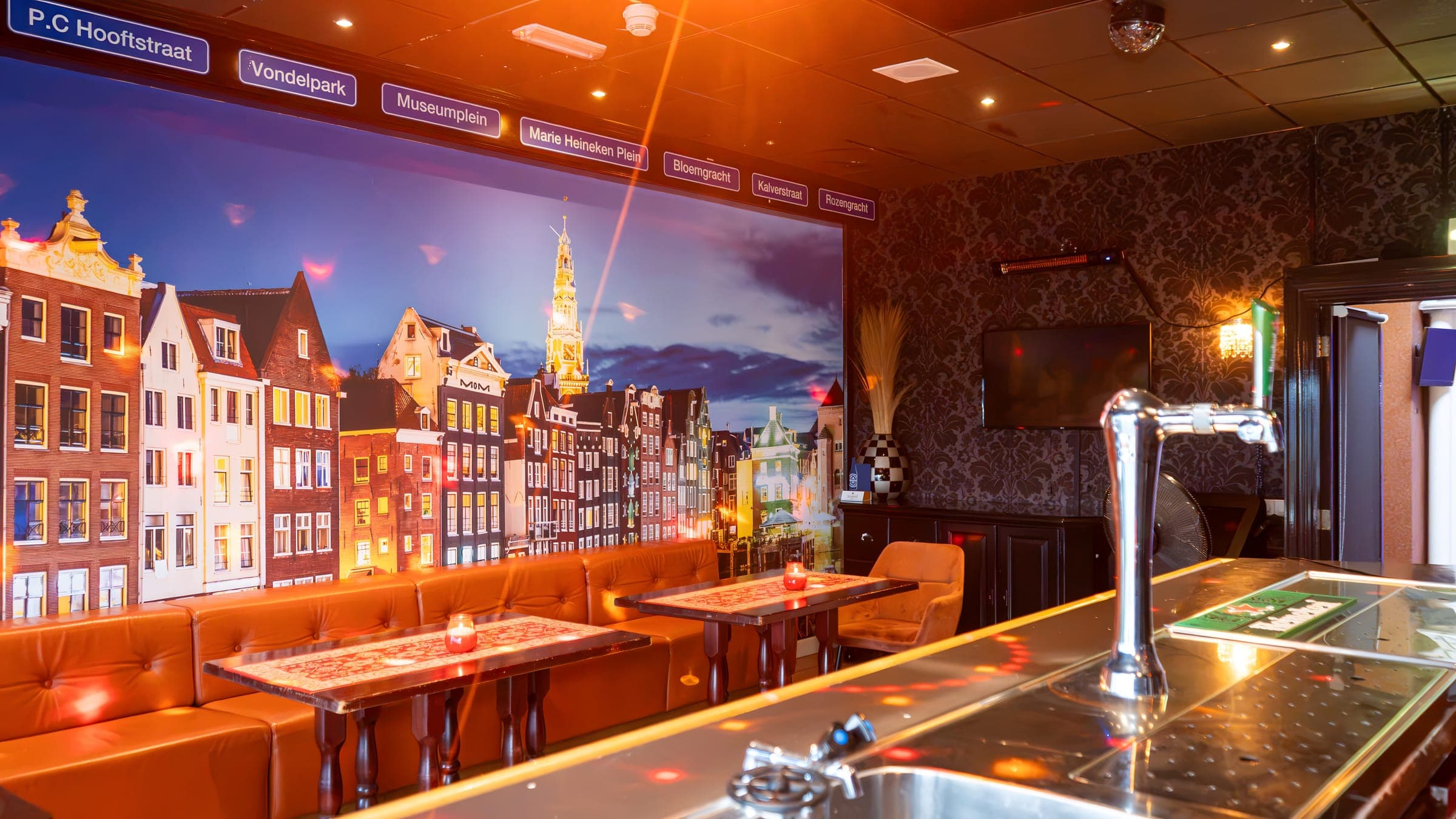 De Jordaanse Karaoke Bar met een wand vol Amsterdamse grachtenpanden en een oranje bank