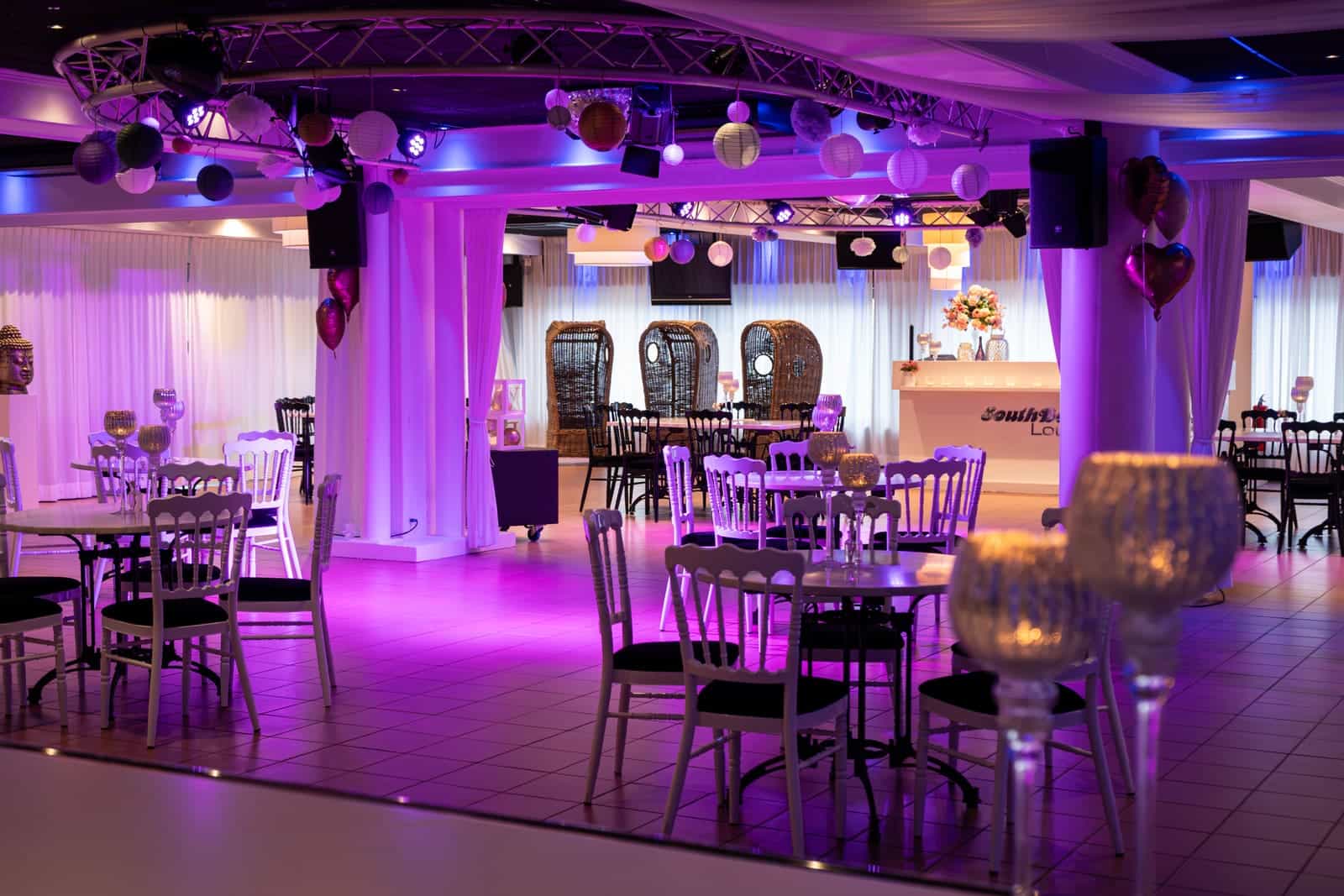 De dansvloer van de South Beach Lounge in paars licht, met tafels en kandelaars ervoor