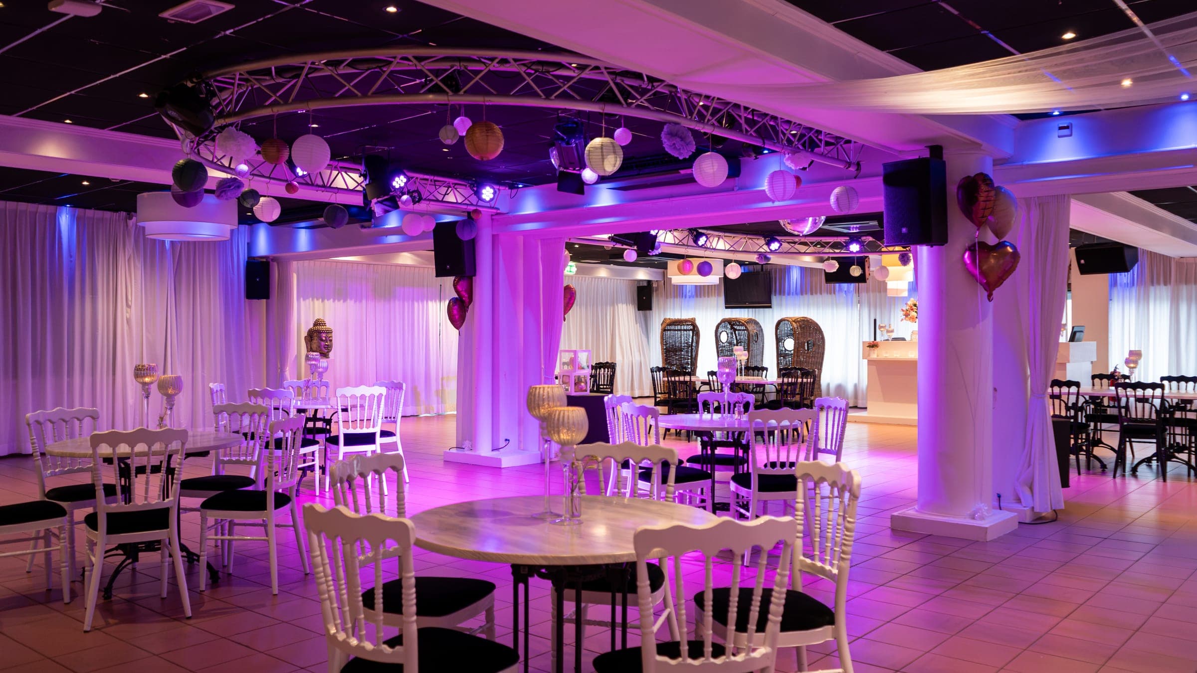 De South Beach Lounge met witte stoelen om ronde tafels, ballonnen en lampionnen aan de ronde truss