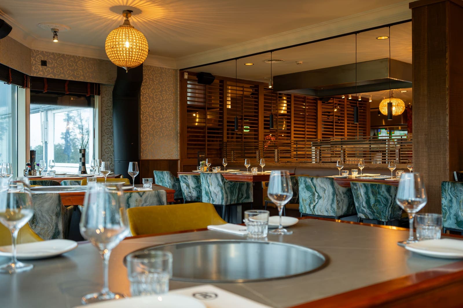 De ronde grillplaat in een gedekte tafel, met wijnglazen ervoor