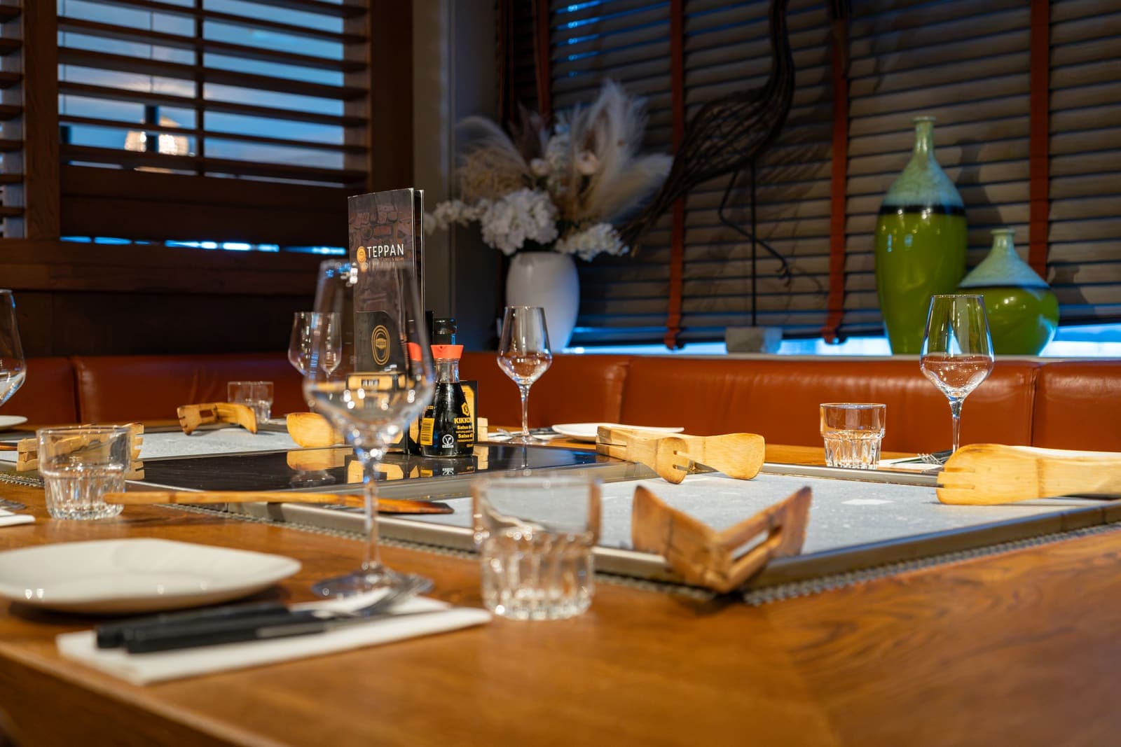 Een gedekte grilltafel met spatels en glazen bij het raam