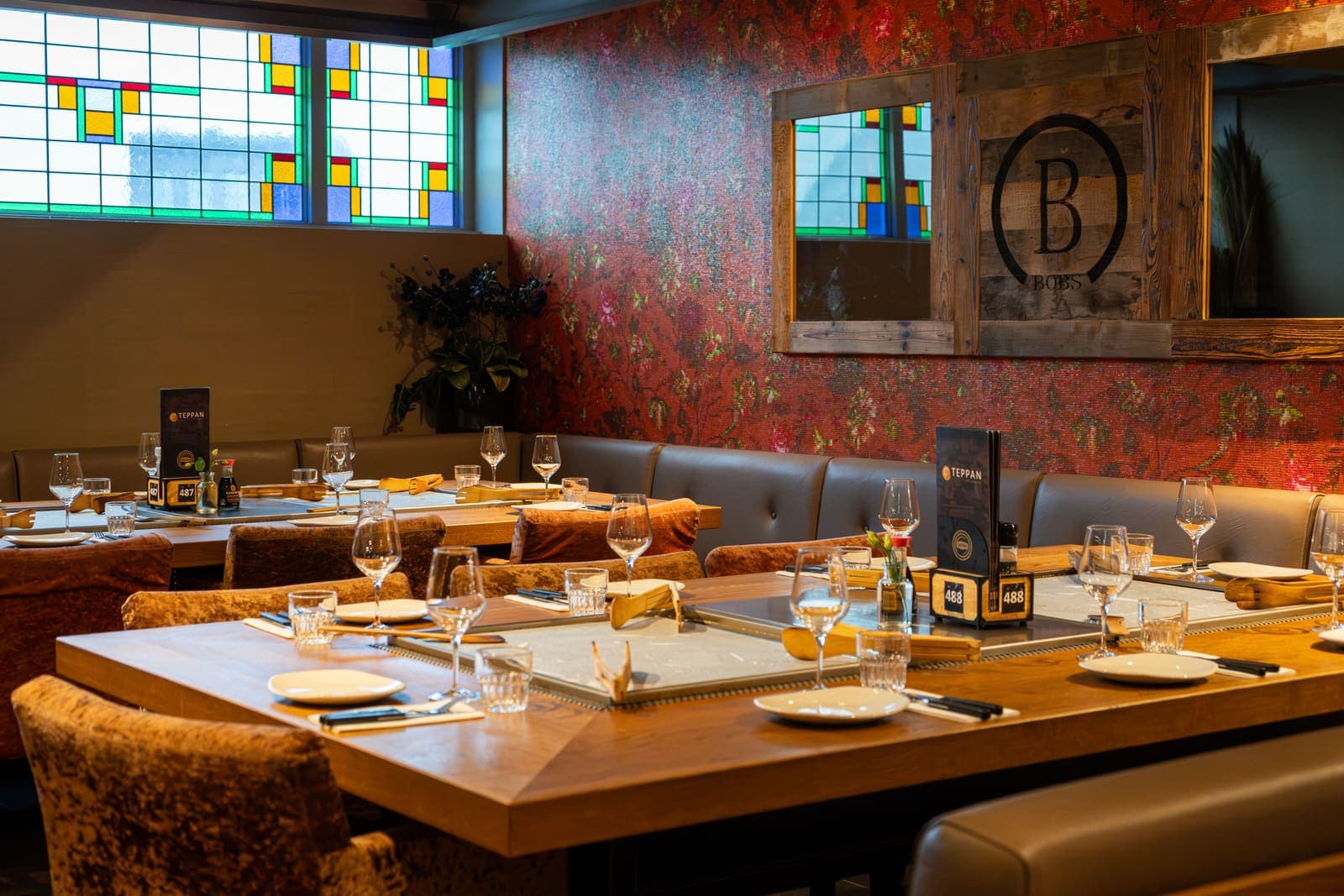 Een gedekte grilltafel voor de wand met glas-in-lood en het B-logo van Bobs