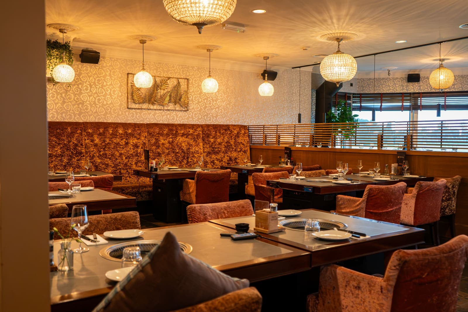 De restaurantzaal van Teppan met roestbruine banken, fluwelen stoelen en gedekte grilltafels