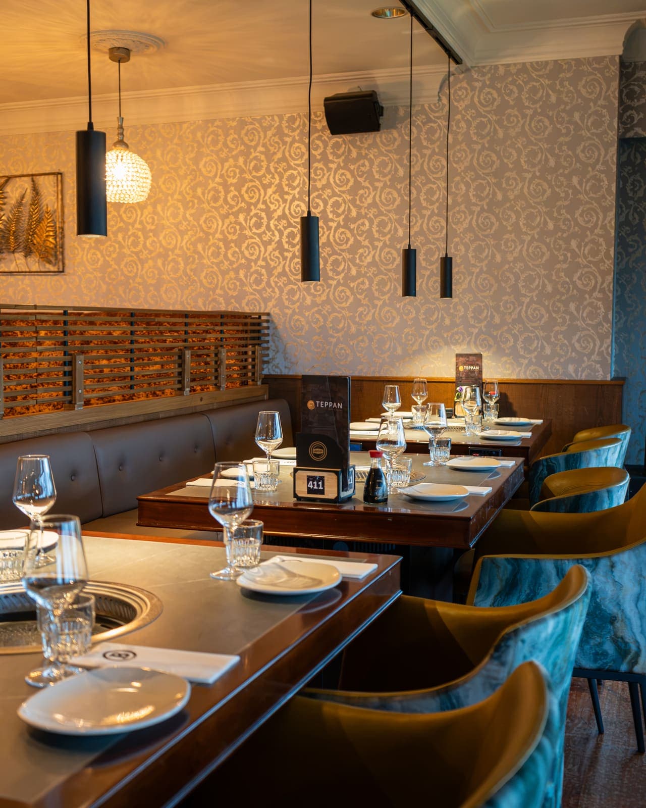 Een gedekte grilltafel onder zwarte hanglampen