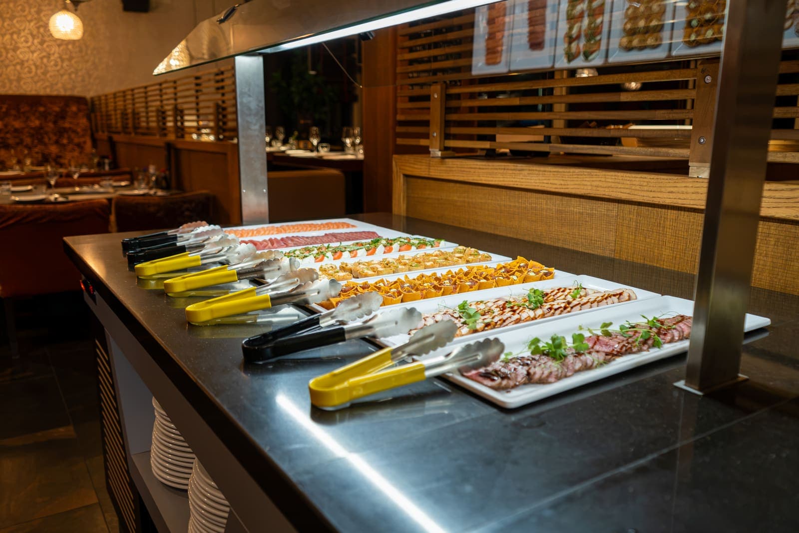 Het buffet met de schalen op een rij en het restaurant erachter