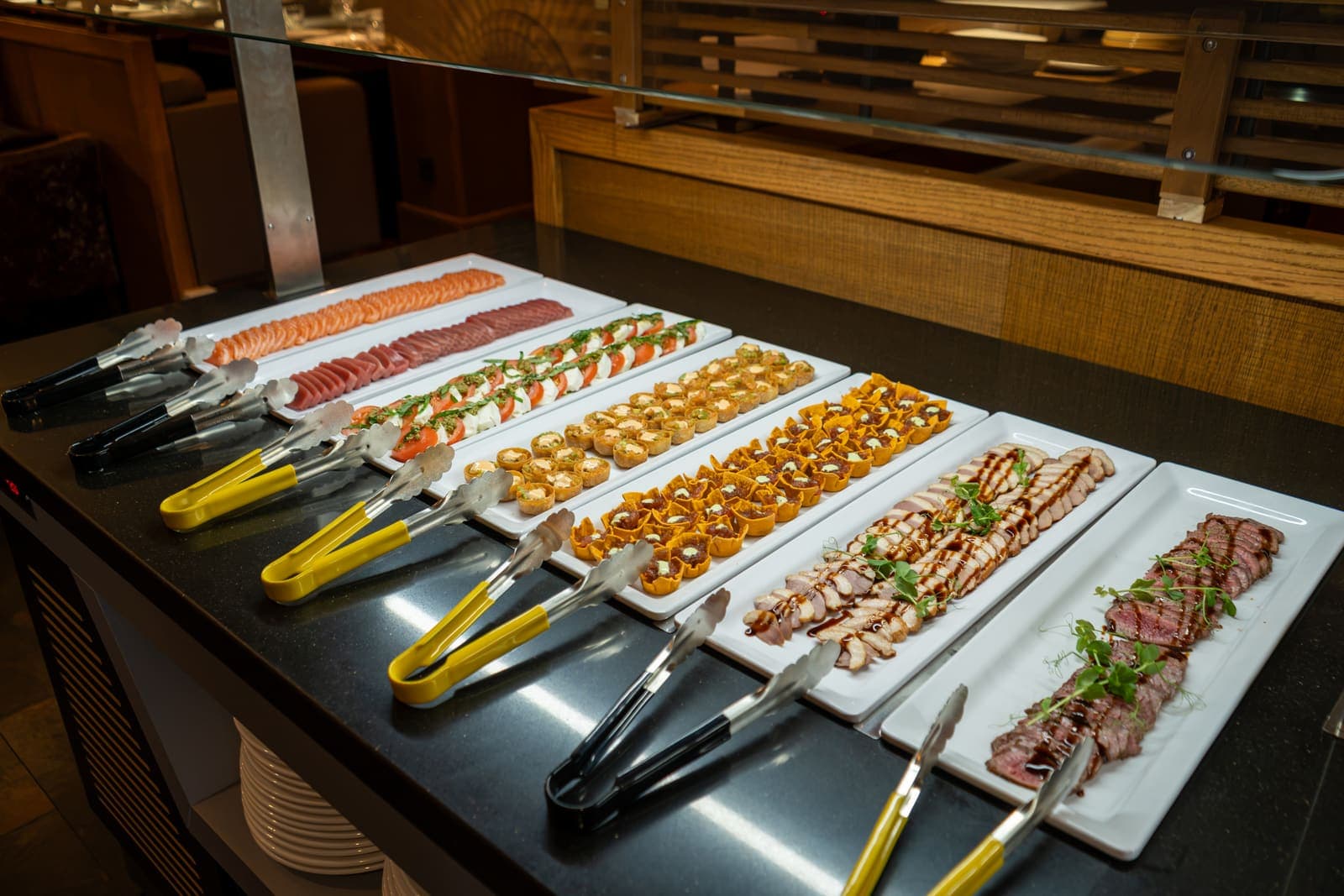 Lange schalen met sashimi, garnalen en dun gesneden vlees op het buffet