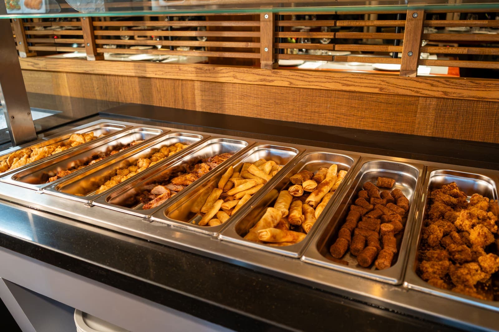Bakken met warme gerechten op het buffet: loempia's, kroketjes en gefrituurde kip