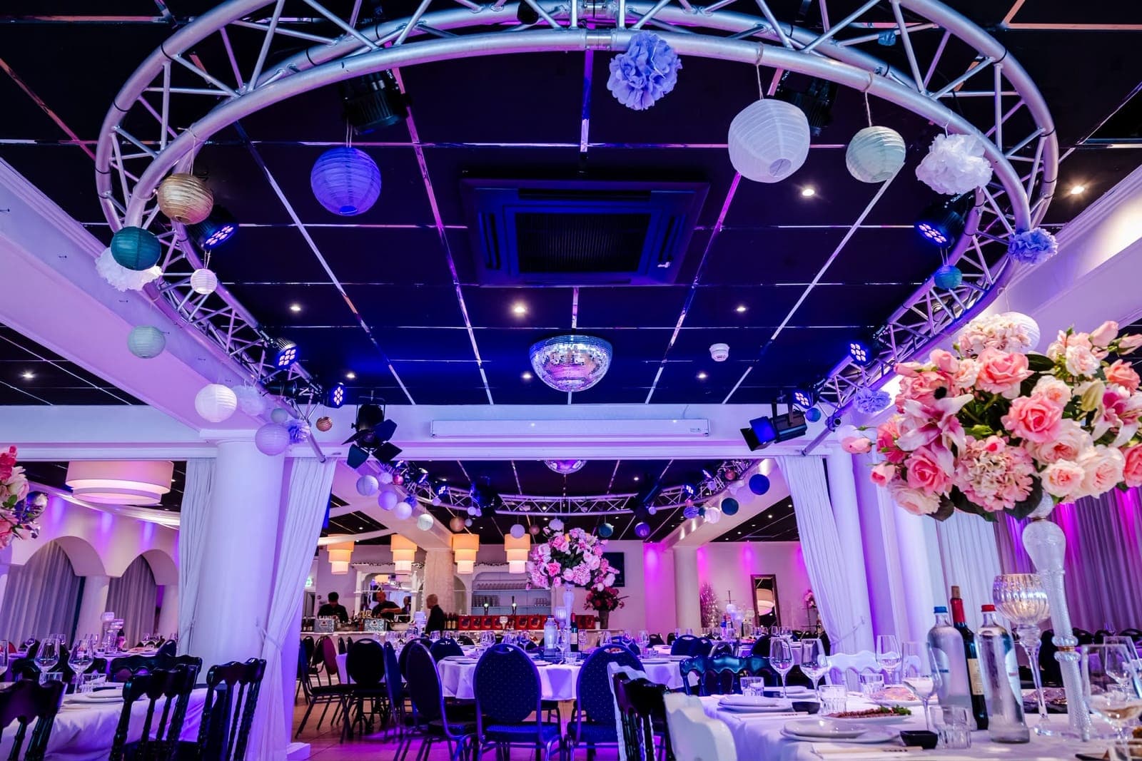 Een ronde tafel met schalen en glazen, in de grote zaal met gekleurd licht erachter