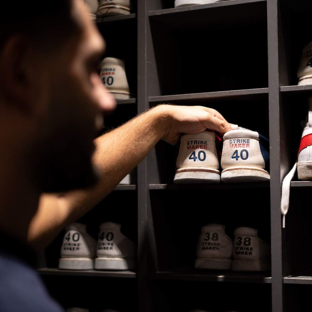 Een gast pakt een paar bowlingschoenen maat 40 uit het rek bij de balie