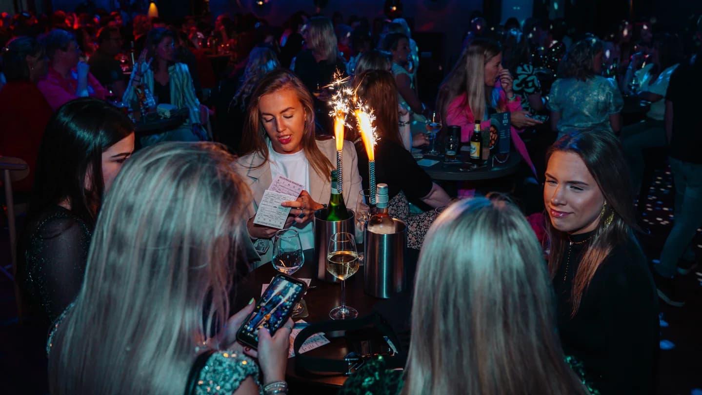 Een gezelschap aan tafel op een thema-avond, met sterretjes op de flessen in de ijsemmer